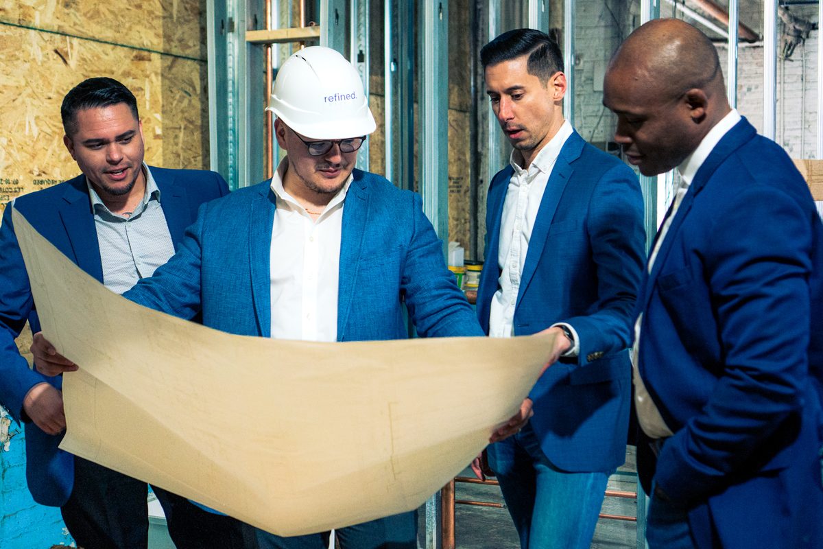 Jose Eduardo Hernandez reviewing building plans with investors on a job site